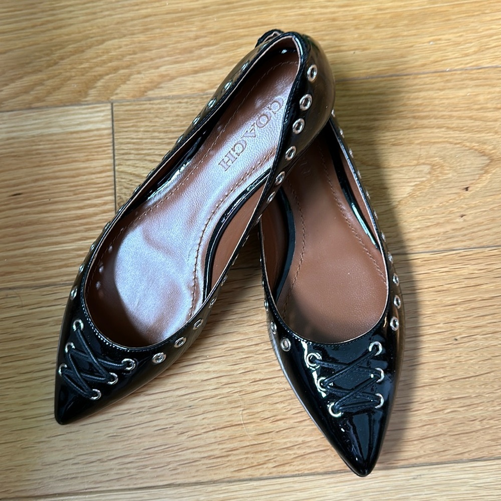 Gorgeous black patent leather Coach ballet flats with silver grommet detail.